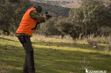 Un montero apunta y dispara con un rifle de cerrojo camo y un punto rojo.